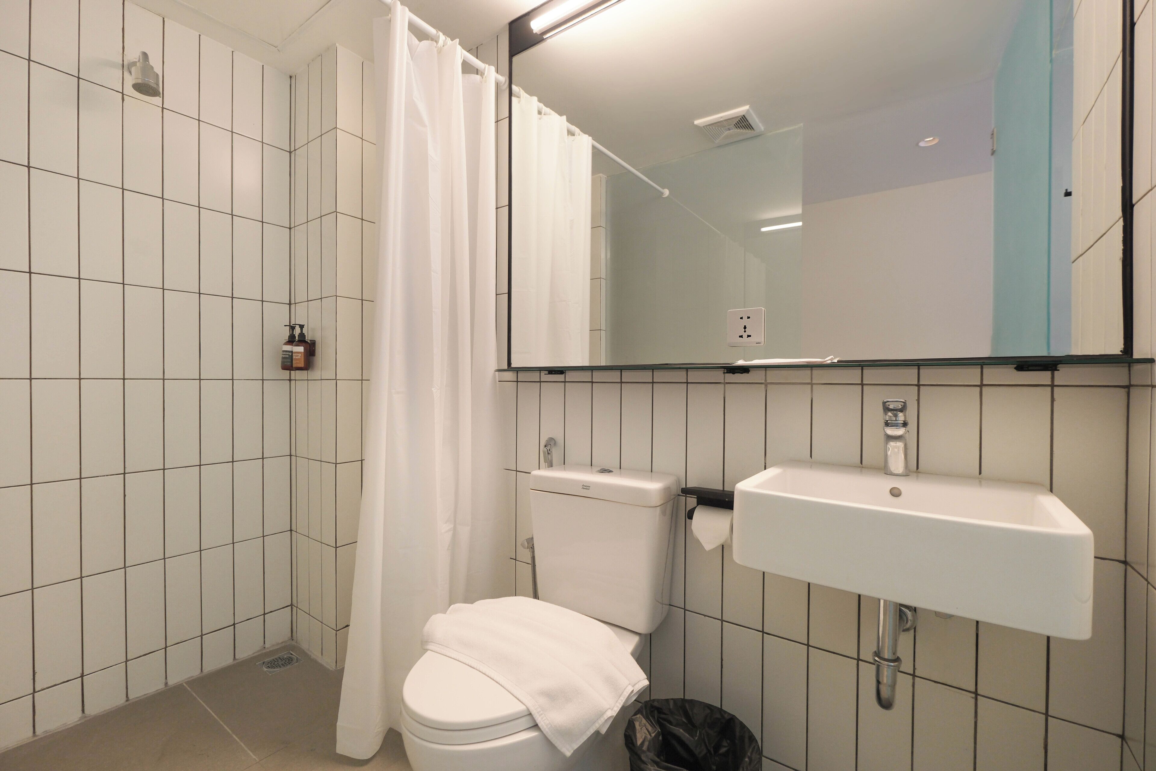 A bathroom with a white toilet, a sink, a mirror, and a shower curtain.