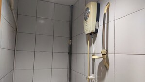 A small, tiled bathroom with a toilet, a shower unit, and a visible pipe. - Hotel O 59 (Sibu)