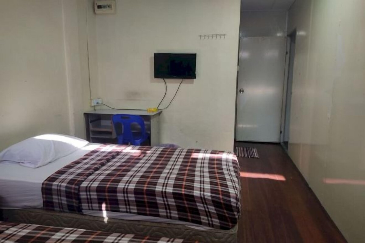 A room with a bed, a TV mounted on the wall, and a door leading to another room.