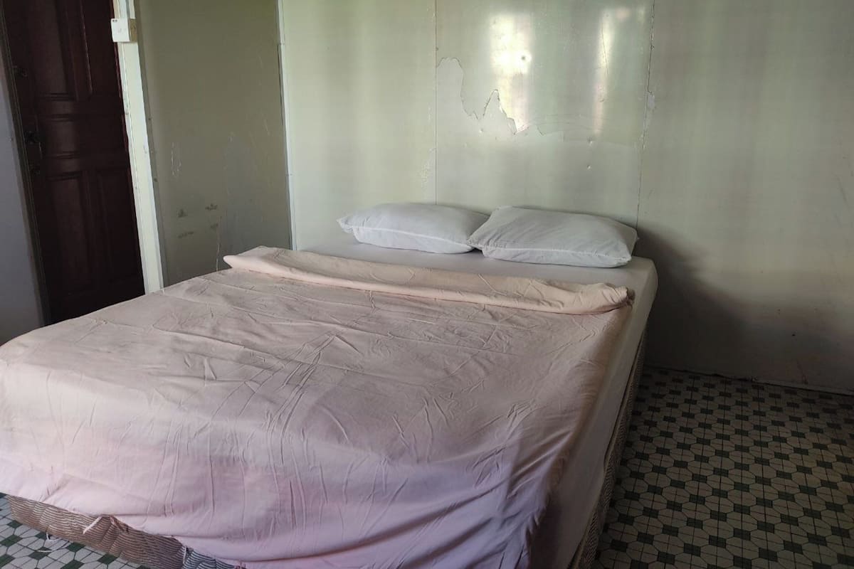 A simple room with a bed, a wooden door, and a tiled floor.