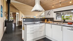 Une cuisine moderne avec des meubles blancs, un dosseret de carreaux noirs et une grande fenêtre.