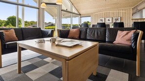 Un intérieur moderne avec un plafond en bois, de grandes fenêtres, un canapé et une table.