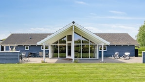 Une maison moderne dotée d’un patio couvert, d’une pelouse et d’un garage.