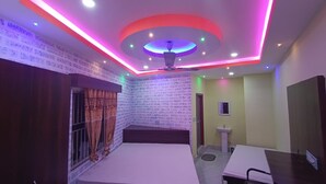 A room with a ceiling fan, a bed, a small table, and a sink. - Hotel Maa Bharati  (Guwahati)