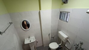 A small, compact bathroom with a toilet, sink, and shower. - Hotel Maa Bharati  (Guwahati)