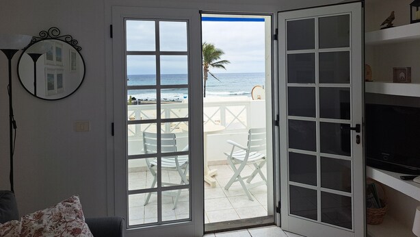 A room with a beach view, a white door, a ceiling fan, and a TV on a shelf. - La Marea Casa en Arrieta, Tranquila. Cerca de Restaurantes y Playas de Arena (CN)