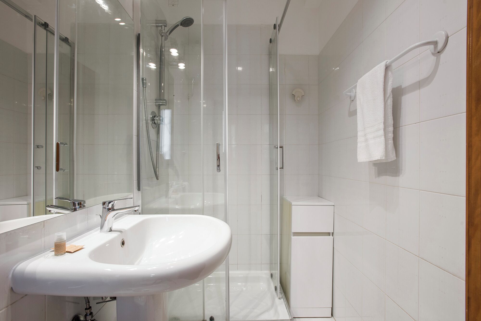 A modern bathroom with a glass-enclosed shower, a white sink, and a white toilet.