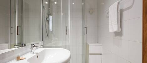 A modern bathroom with a glass-enclosed shower, a white sink, and a white toilet.