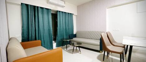 Una sala de estar moderna con un sofá, dos sillones, una mesita redonda y un ventilador de techo.