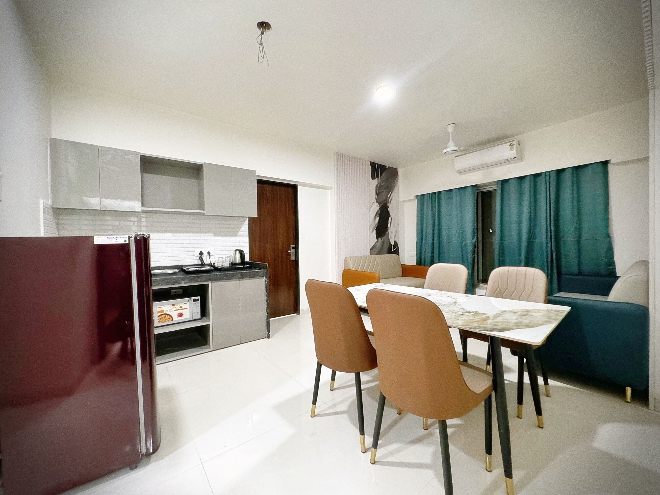 Uma cozinha moderna com armários brancos, uma geladeira e um espaço de jantar com mesa e cadeiras.