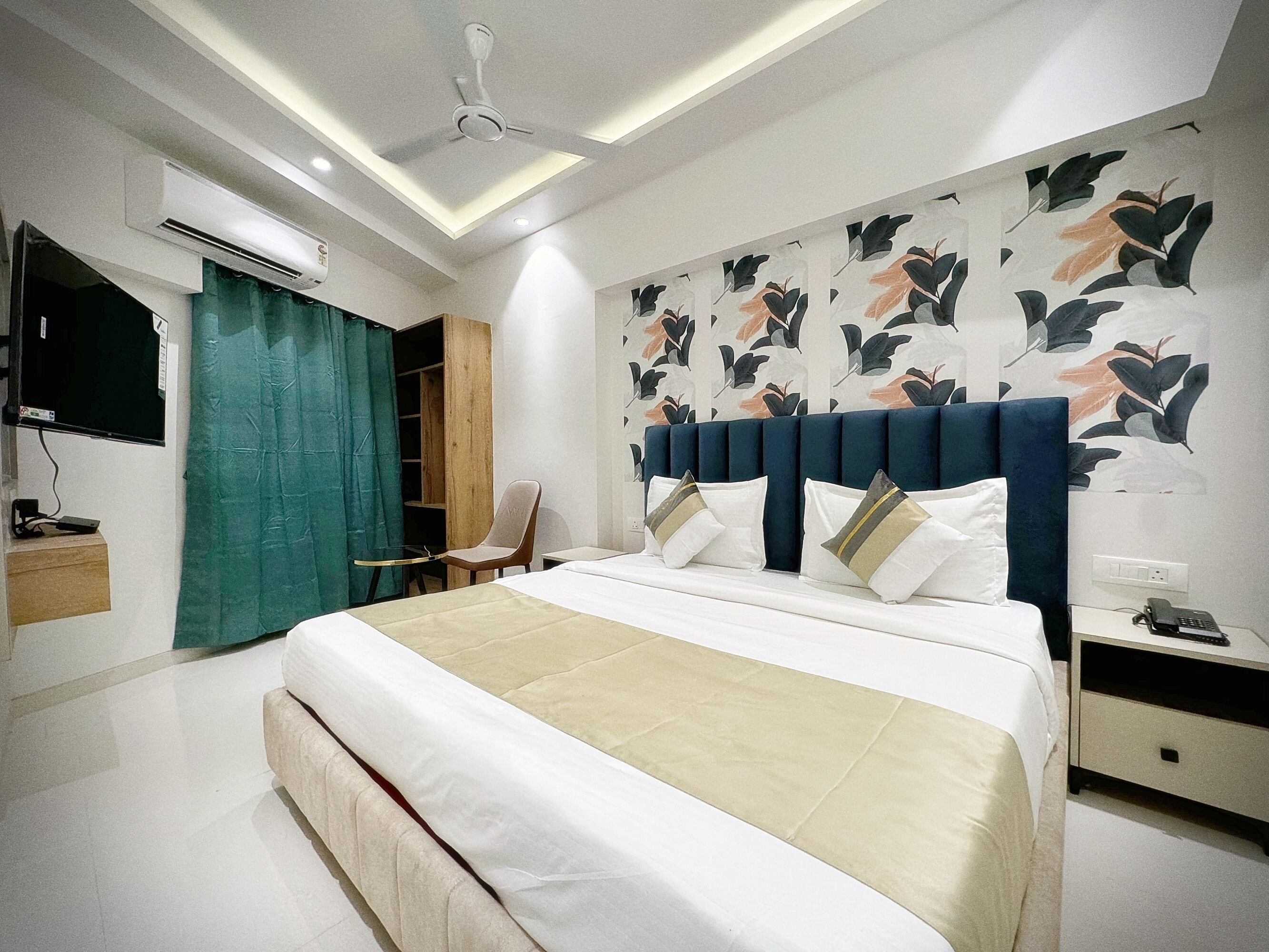 Una habitación de hotel moderna con una cama grande, un escritorio, una silla y un ventilador de techo.