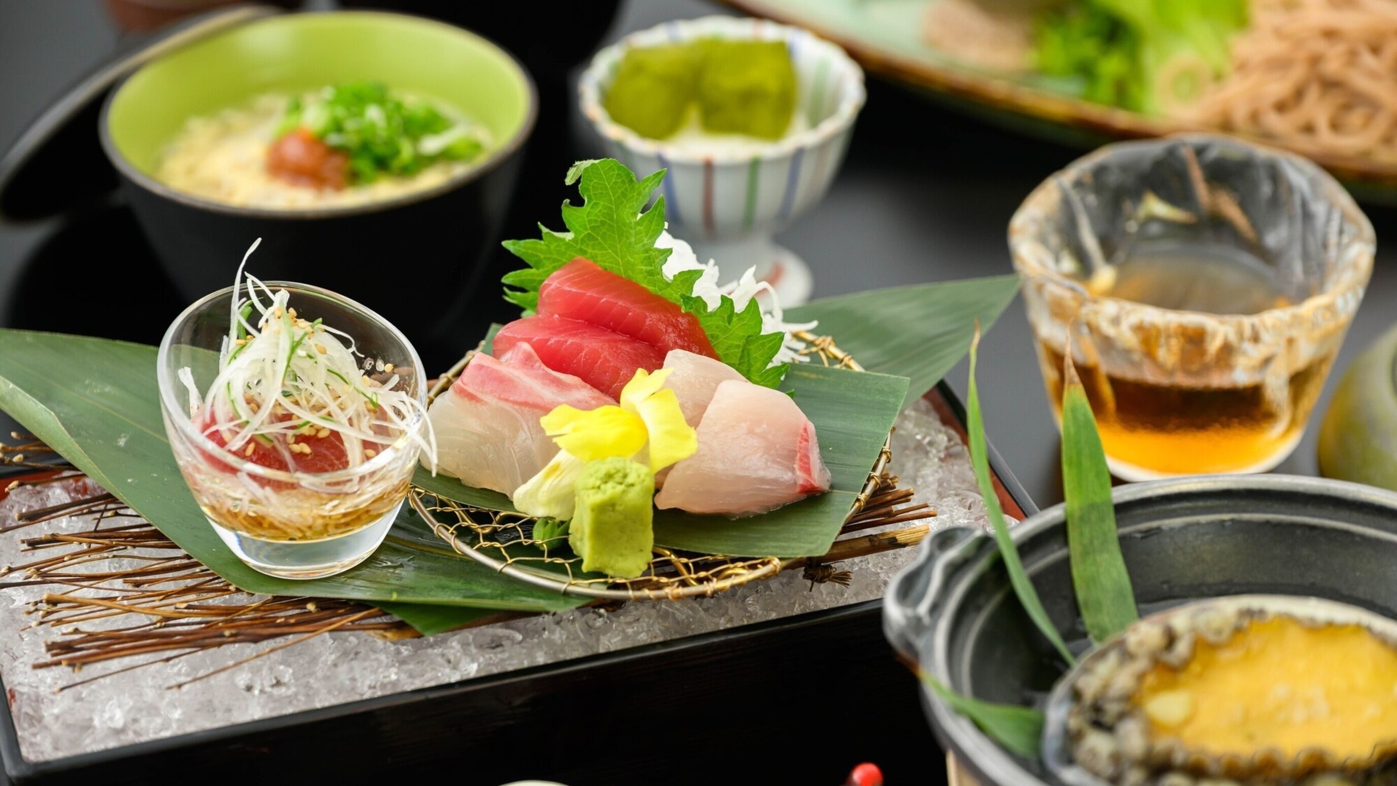 A variety of dishes including sashimi, a bowl of soup, and a small dish with a sauce.