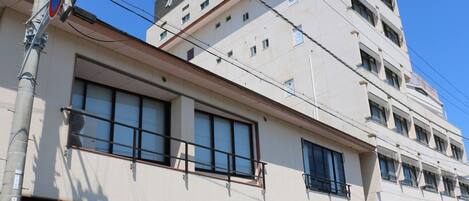 A multi-story building with a flat facade, large windows, and a traditional-style awning at the entrance.