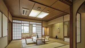 Una tradizionale stanza giapponese con pavimentazione in tatami, porte scorrevoli e un tavolino con sedie.