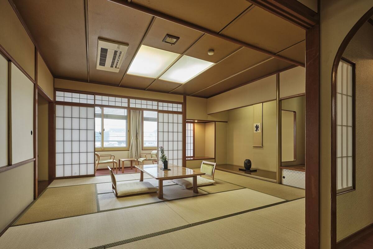 A traditional Japanese room with tatami flooring, sliding doors, and a low table with chairs.