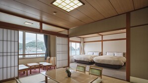 Una camera tradizionale in stile giapponese con pavimento in tatami, un tavolino di legno e due letti con biancheria bianca.