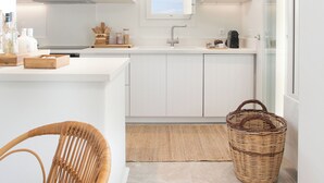 Una cocina moderna con armarios blancos, una isla central e iluminación colgante.