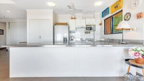 A modern kitchen with white cabinetry, a central island, and a dining area with a table and chairs.
