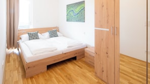 A bedroom with a wooden bed, a nightstand, a wardrobe, and a painting on the wall.