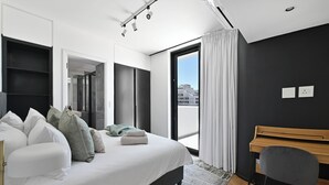 A modern bedroom with a large bed, a desk, and a view of the city through a large window. - City Centre Rooftop Penthouse with 360° City & Mountain Views! (Cape Town)