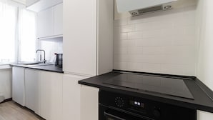 Une cuisine moderne avec des meubles blancs, un plan de travail noir et un four encastré.