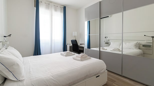 Une chambre d’hôtel moderne, dotée d’un grand lit, d’un bureau et d’une armoire.