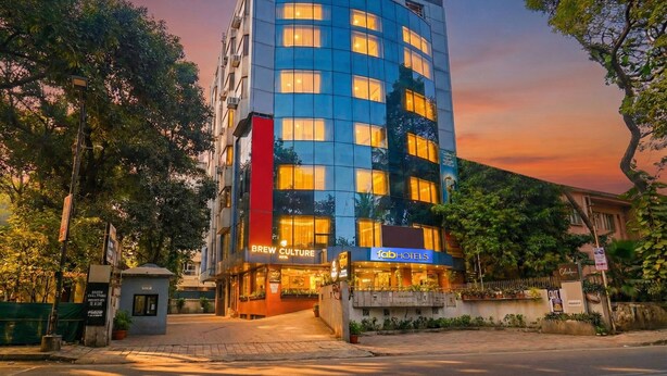 A modern hotel with a glass facade, multiple floors, and a well-lit entrance. - Oriva Deccan 8 (Pune)