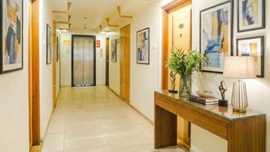 A hotel hallway with a wooden console table, framed artwork, and a potted plant. - Oriva Deccan 8 (Pune)