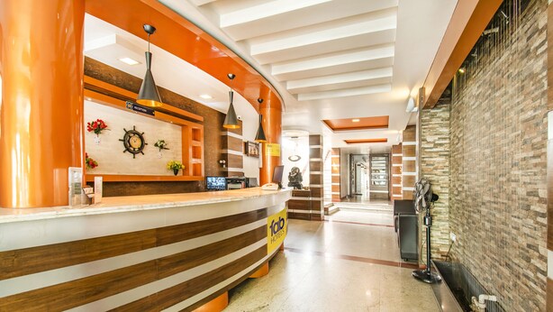 Un espace d’accueil d’hôtel au design moderne, comprenant un comptoir d’accueil, une horloge et un panneau indiquant la réception.