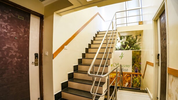 Una escalera con barandales de metal, una puerta con la etiqueta '204' y un letrero que indica '4 Seasons'.