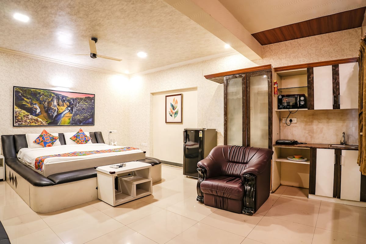 Un dormitorio con cama, escritorio, silla, refrigerador y microondas.