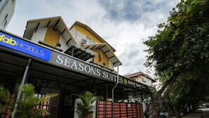 Un hotel llamado 'Seasons Suites' con una entrada cubierta y un letrero que dice 'Fab Hotels'.