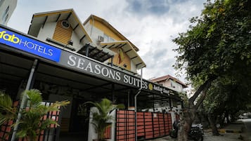 Een hotel genaamd 'Seasons Suites' met een overdekte ingang en een bord met 'Fab Hotels'.