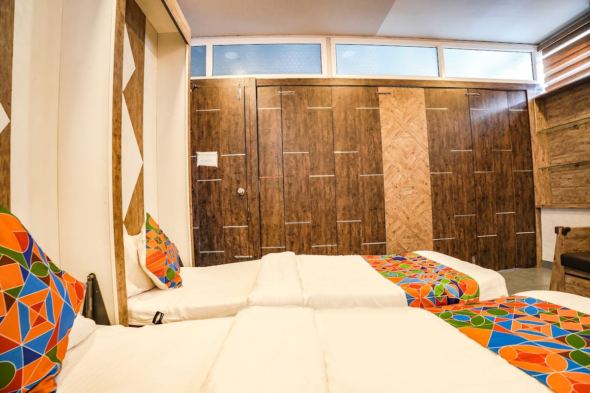Habitación de hotel con dos camas, un armario de madera y una ventana con persianas.