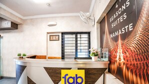 Una recepción con un logotipo de 'fab hotels' y una pared con un cartel que anuncia '4 SEASONS SUITES NAMASTE'.