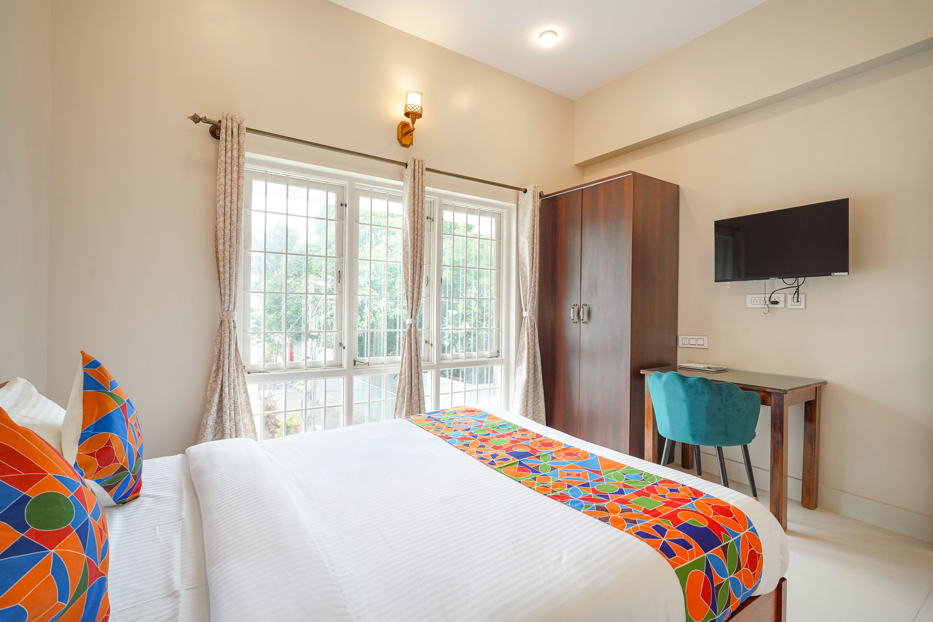Una habitación de hotel con cama, escritorio, silla, armario y televisor.