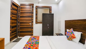 Une chambre à coucher avec un lit, une armoire en bois, un meuble sombre et une petite table avec un téléphone.