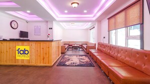Rebedor d'hotel amb taulell de recepció, un sofà, una taula de centre i una catifa amb dibuixos.