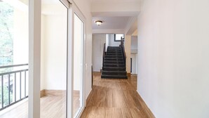 Un passadís espaiós amb sòl de fusta que condueix a una escala.