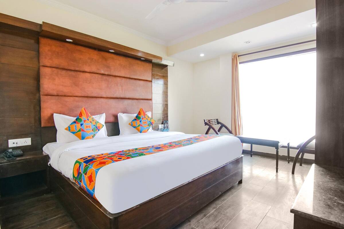 Amplia habitación de hotel con una cama grande, cabecero de madera y vistas al exterior.