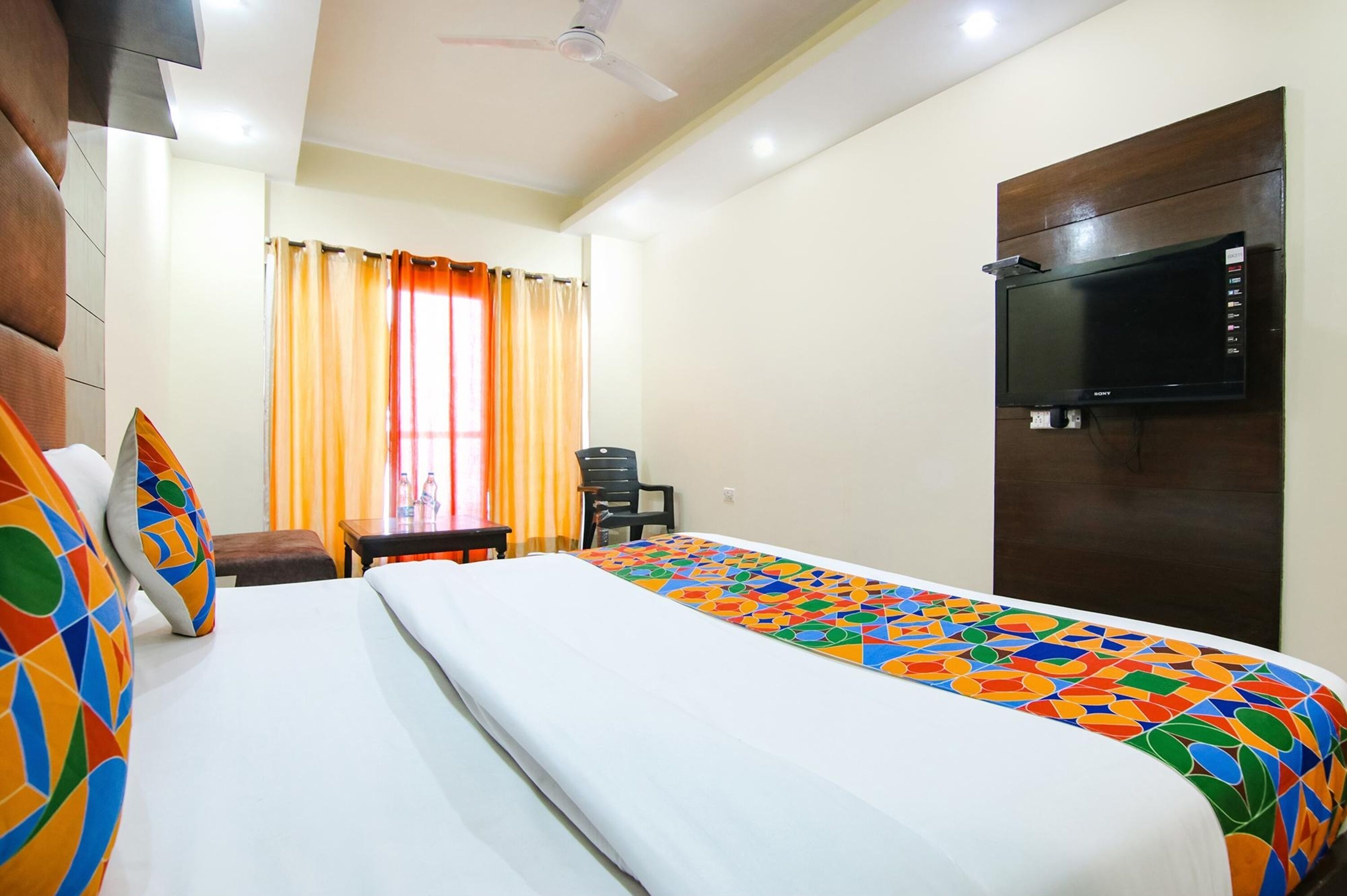 A hotel room with a bed, a TV mounted on the wall, a desk, and a chair.