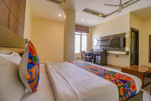 A hotel room with a bed, a desk, a television, and a window. - Fabhotel Narula (Dehradun)