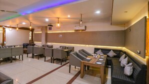 A modern restaurant with a mix of dining tables and seating areas, including a sofa and chairs. - Fabhotel Narula (Dehradun)