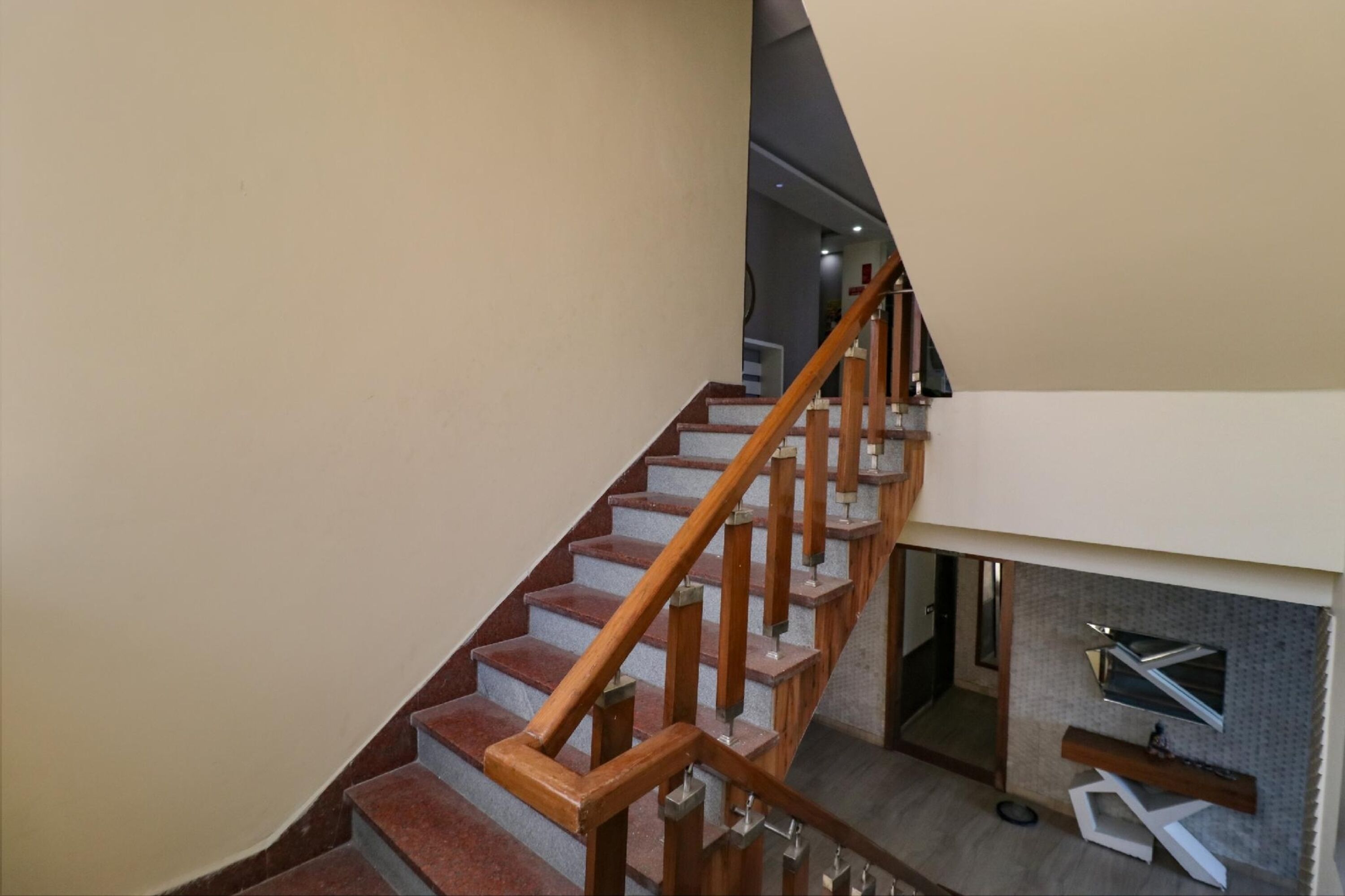 A staircase with wooden handrails and red steps, leading to an upper floor.