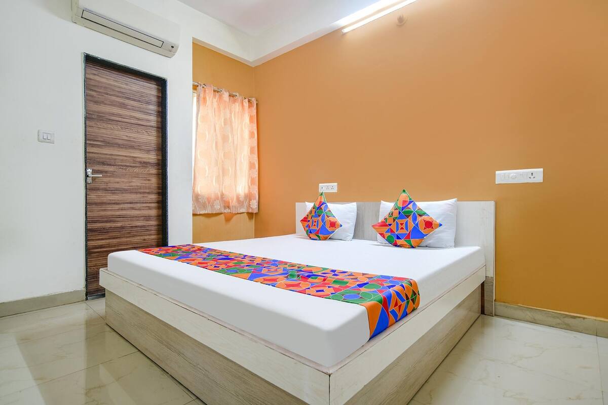 A bedroom with a large bed, a wooden door, and a curtain.