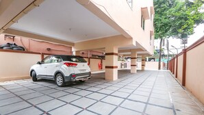 A white SUV parked in a covered parking area with tiled flooring and a beige wall. - Fabhotel Fortune Begumpet (Hyderabad)