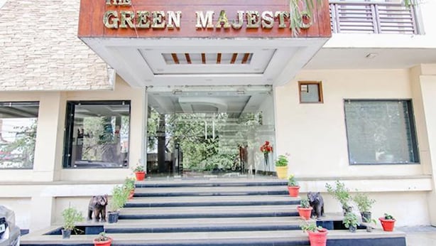 The entrance of The Green Majestic with a set of steps leading up to the entrance, flanked by potted plants. - Fabhotel The Green Majestic (Dehradun)