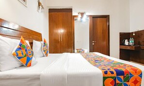 Ein Hotelzimmer mit einem Bett, zwei Holzschränken, einem Schreibtisch mit Wasserkocher und einem Nachttisch.