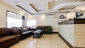 A modern lobby with leather sofas, a reception desk, and framed pictures on the wall. - Fabhotel The Green Majestic (Dehradun)