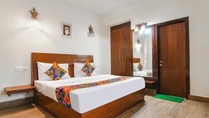 A bedroom with a wooden bed, a nightstand, a mirror, and a wardrobe. - Fabhotel The Green Majestic (Dehradun)